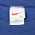 Nike neck tag with red Swoosh, size L, and Made in U.S.A. text inside blue sweatshirt