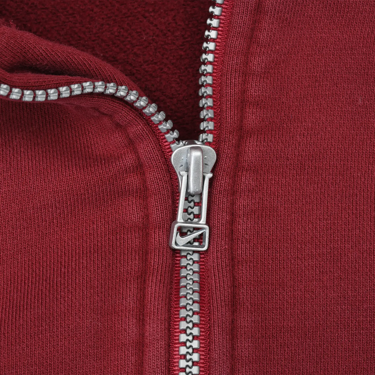 Close-up of silver Nike quarter-zip pull and burgundy fabric