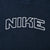 Close-up of white outlined Nike spellout embroidery across the navy fleece chest