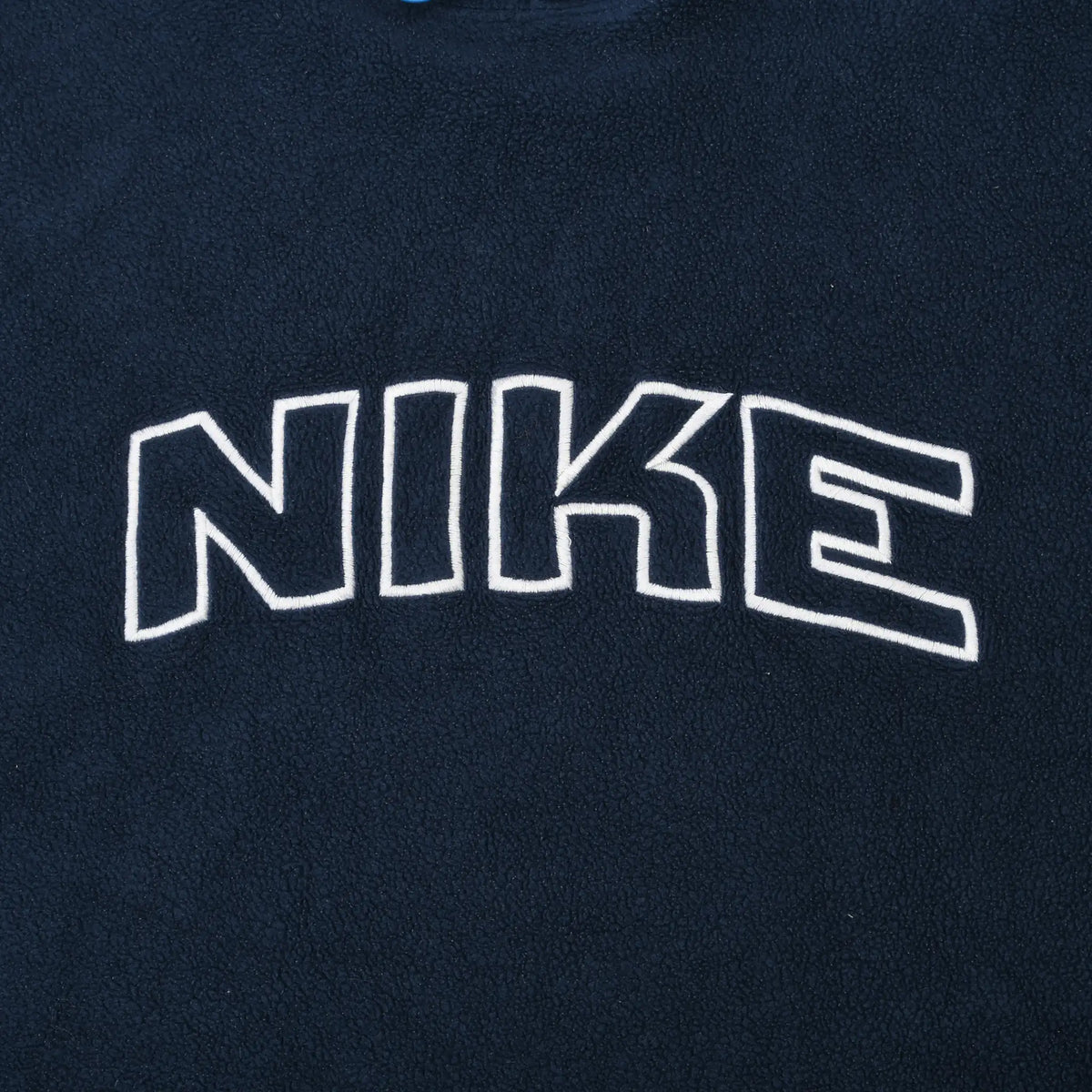 Close-up of white outlined Nike spellout embroidery across the navy fleece chest