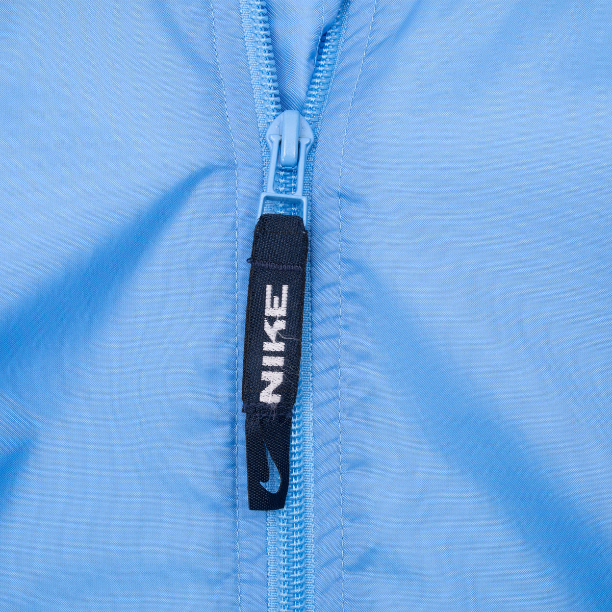Close-up of blue zipper with navy Nike logo pull tab