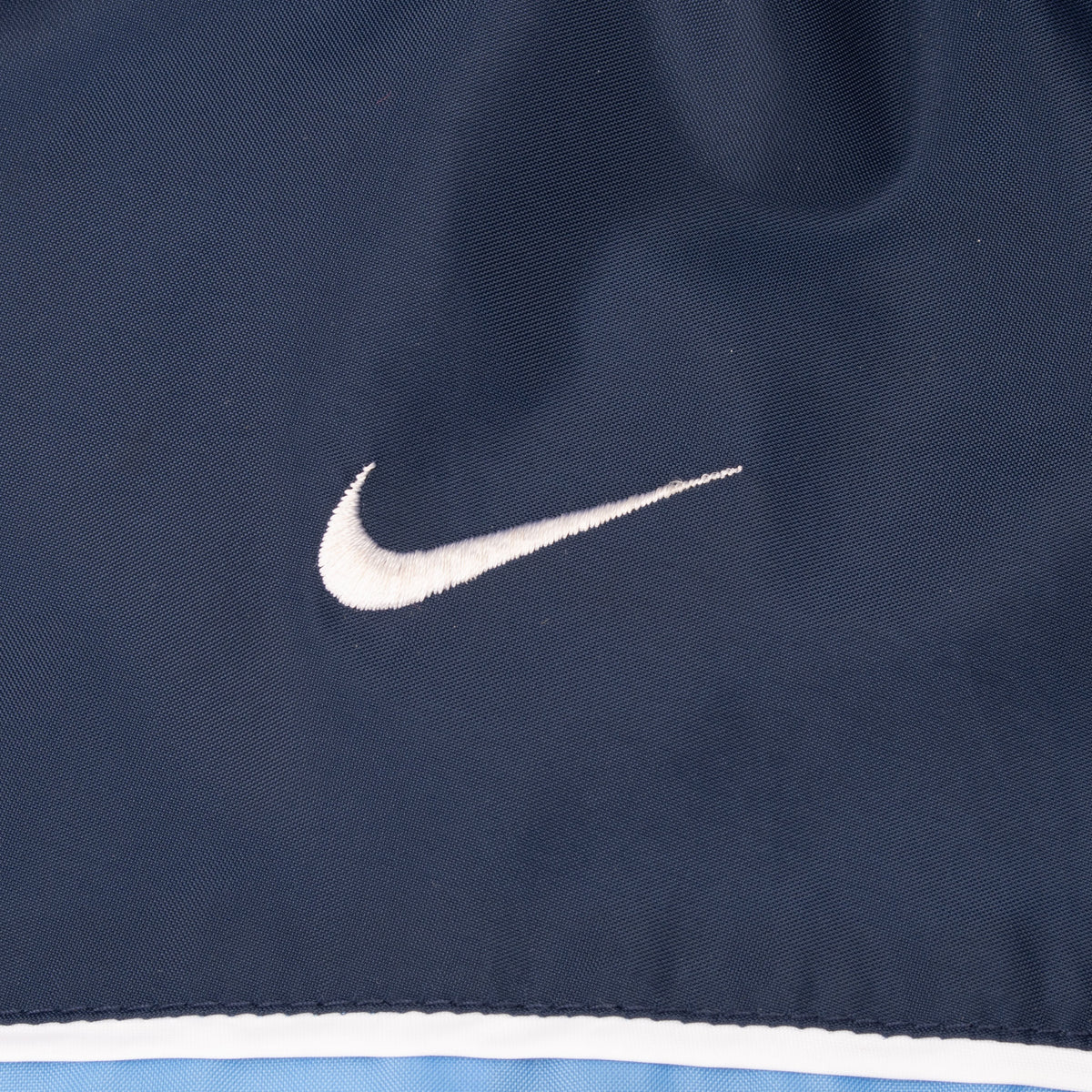 Close-up of white Nike Swoosh embroidery on navy fabric