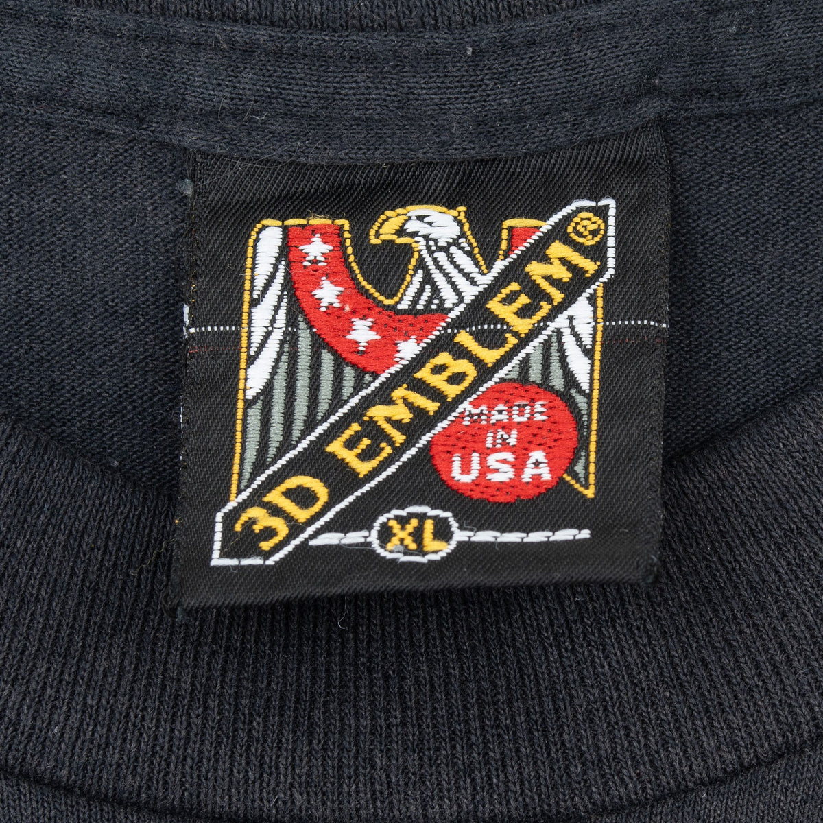 Close-up of 3D Emblem XL eagle neck tag on black T-shirt