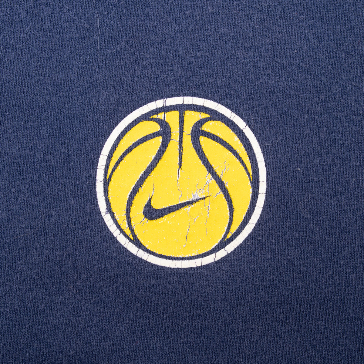 Close-up of yellow basketball and Nike Swoosh chest graphic on navy fabric