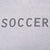 Close-up of dark SOCCER lettering printed across the grey tank top back