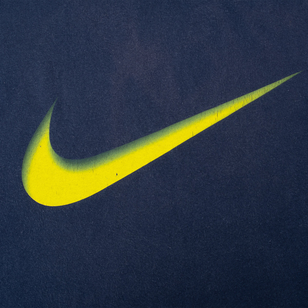 Close-up of yellow-to-green Nike Swoosh print on blue fabric