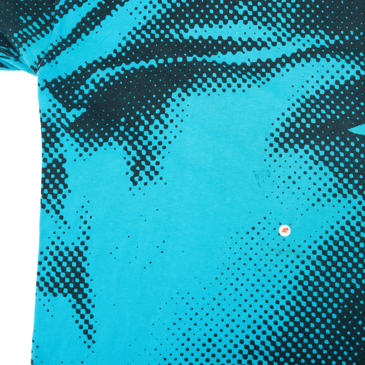 Close-up of black halftone print on turquoise fabric with a small marked flaw
