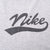 Close-up of black script Nike spellout and underline chest graphic on grey fabric