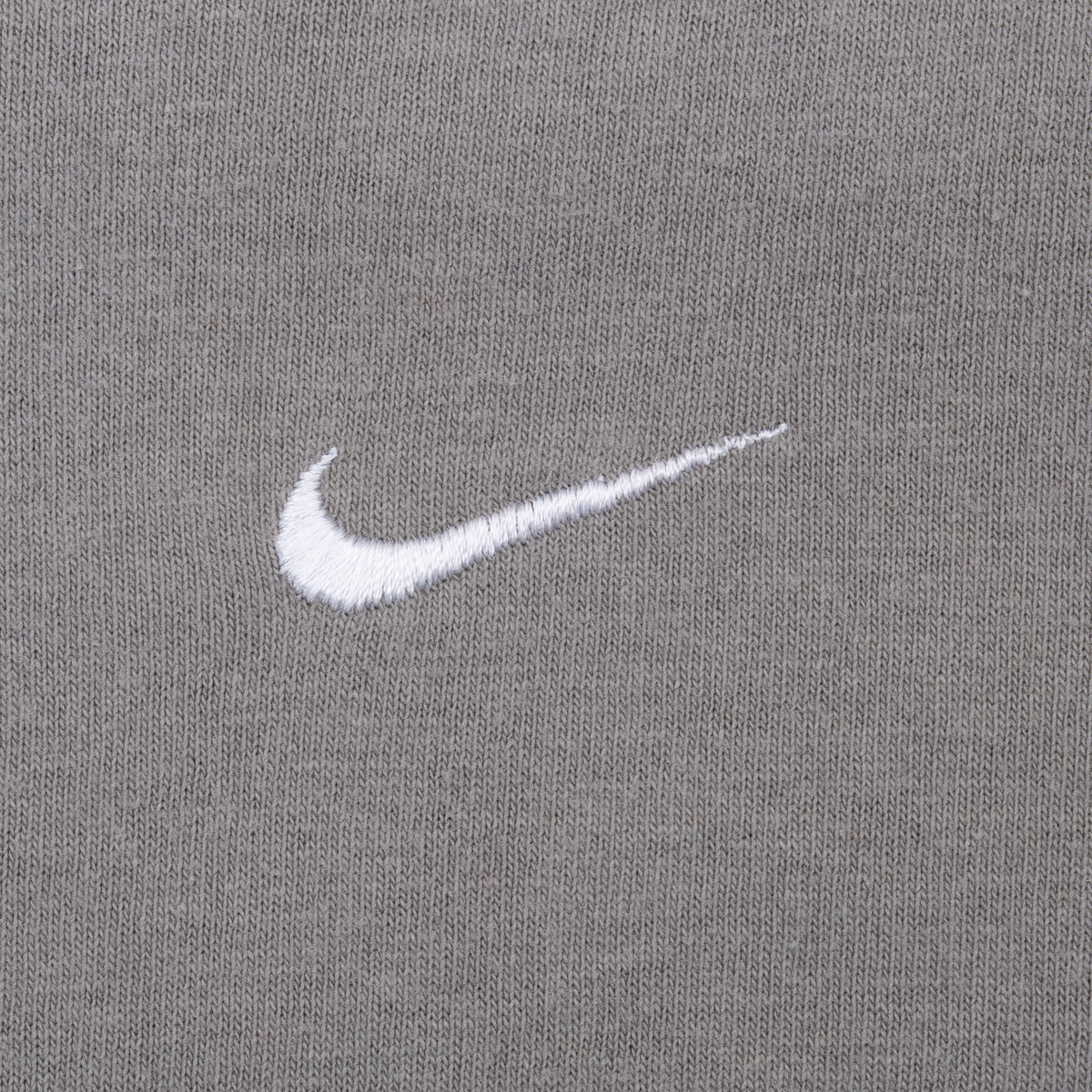 Close-up of white embroidered Nike Swoosh on grey chest fabric