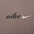 Close-up of black Nike spellout embroidery and white Swoosh on brown fabric