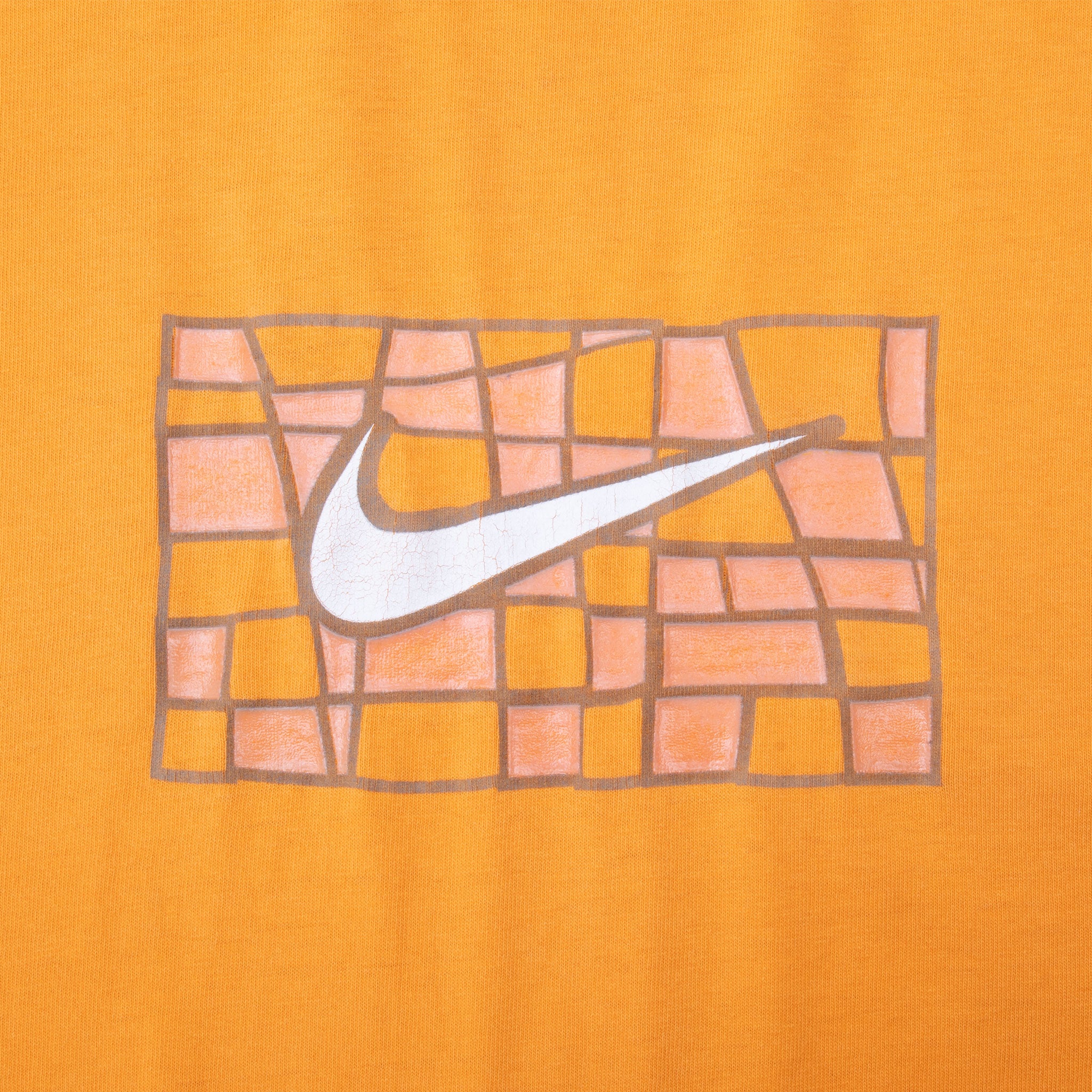 Close-up of white Nike Swoosh over abstract orange and brown grid print