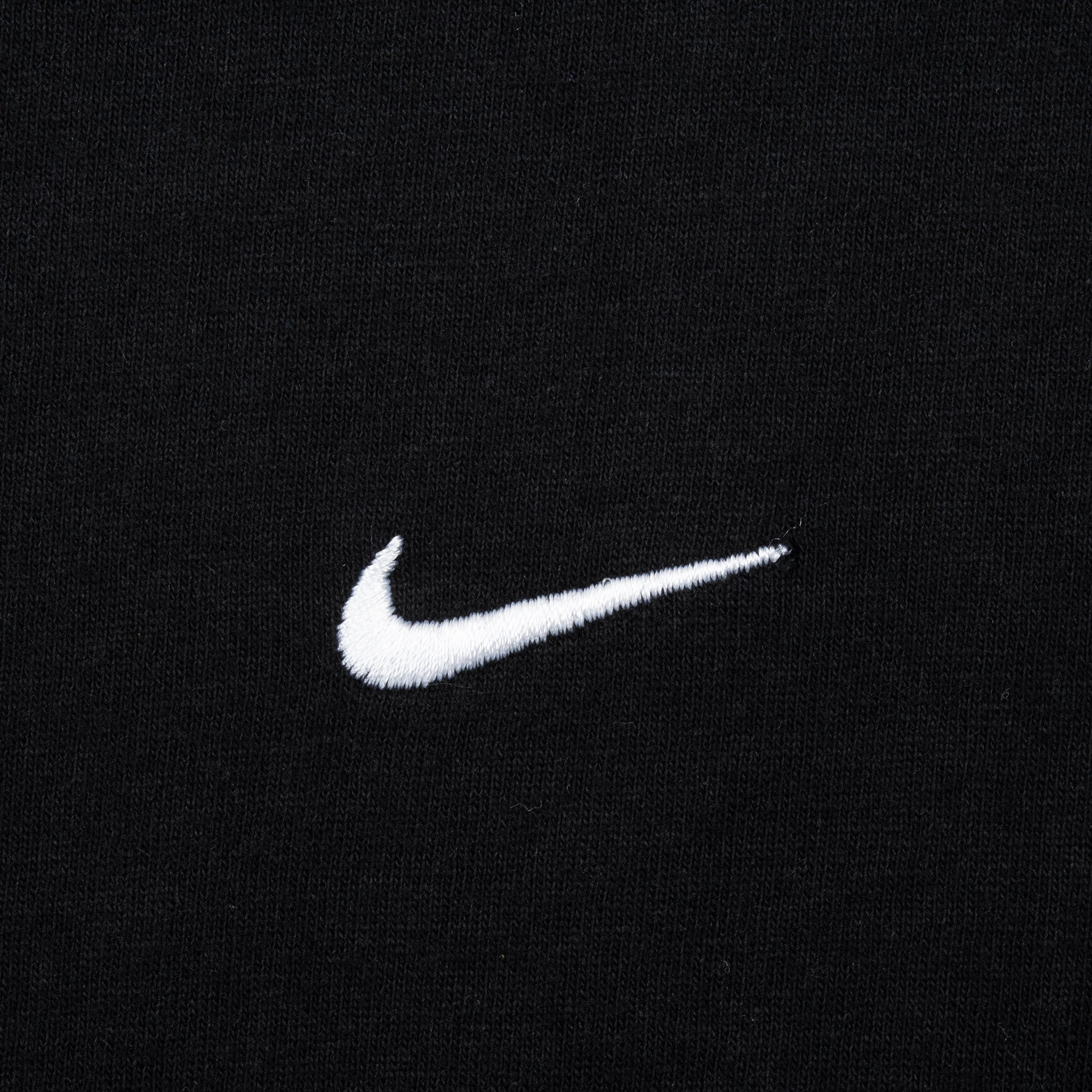 Close-up of white embroidered Nike Swoosh on black fabric