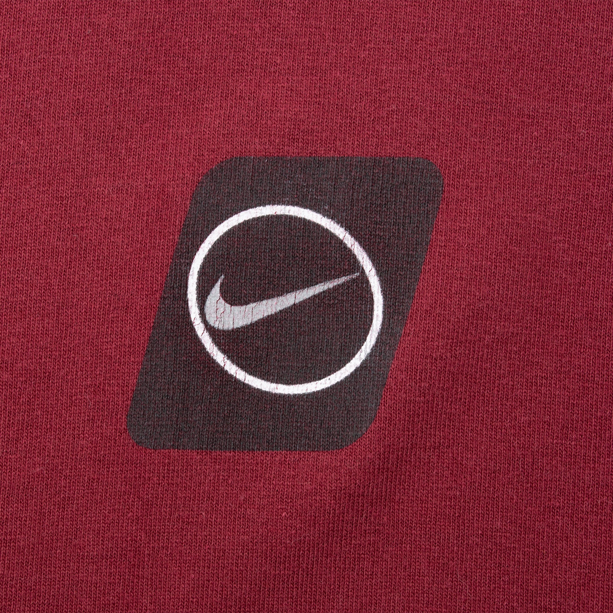 Close-up of black-and-white circular Nike Swoosh print on burgundy fabric