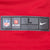 Close-up of size L Nike NFL and NFL Players hem label on red jersey fabric