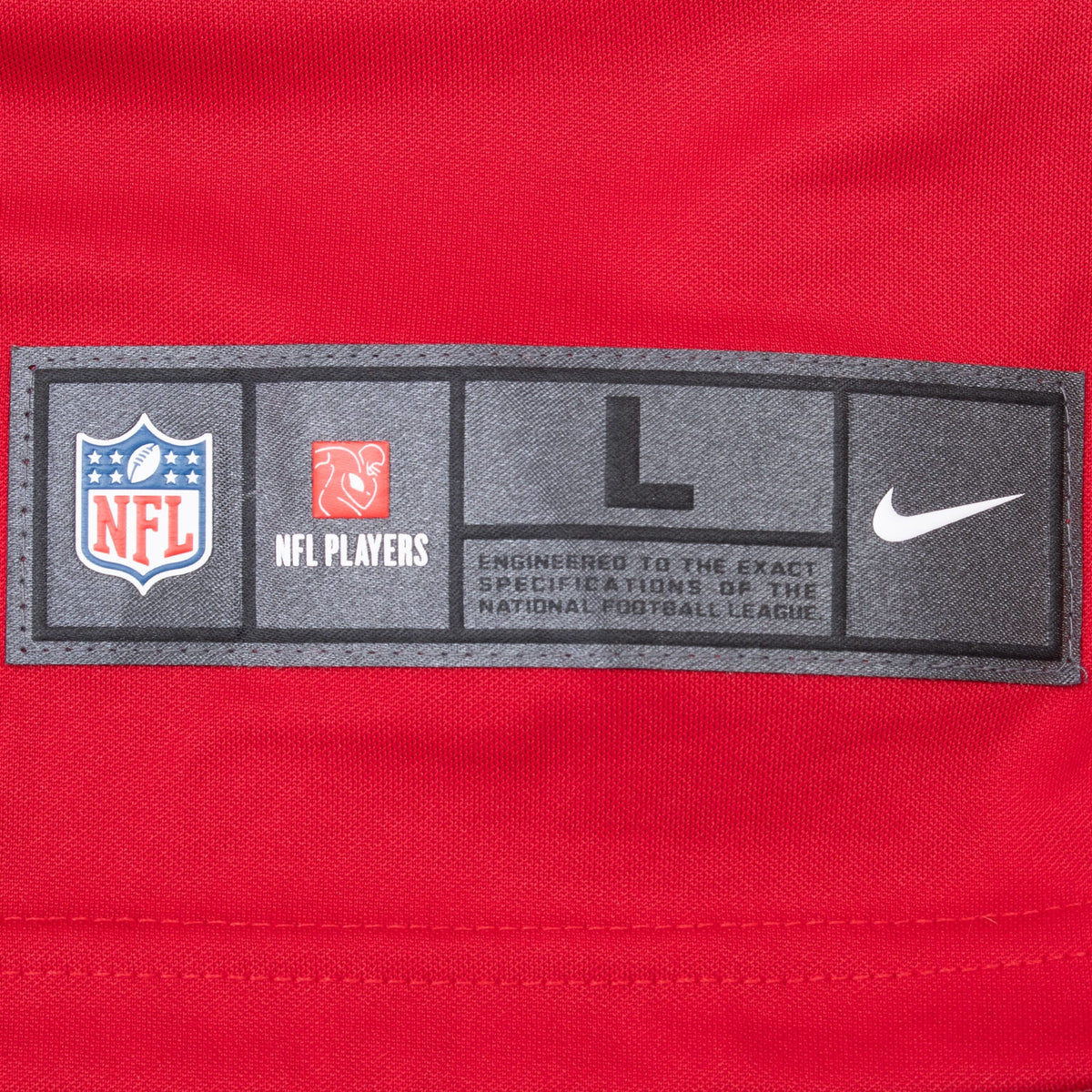 Close-up of size L Nike NFL and NFL Players hem label on red jersey fabric