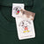 Close-up of Mickey & Co. neck label and hangtags on dark green T-shirt