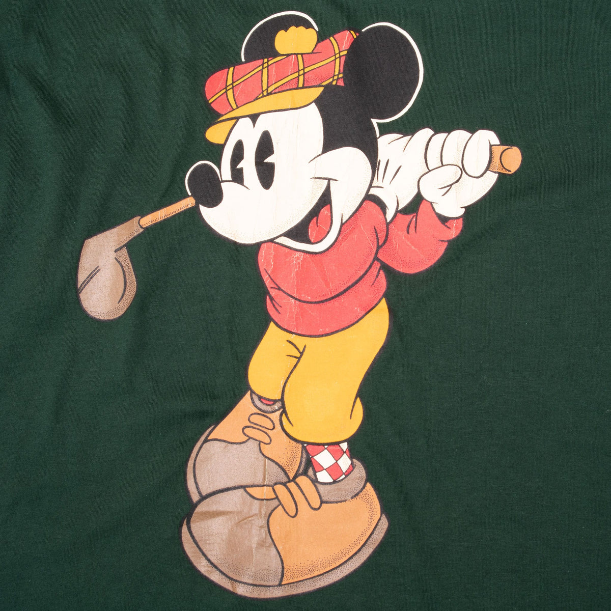 Close-up of Mickey Mouse in golf attire swinging a club on dark green T-shirt