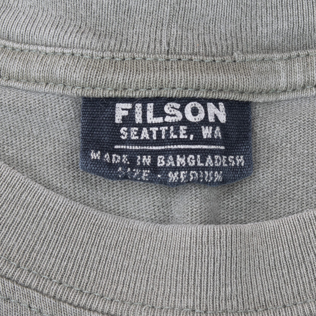 Close-up of Filson Seattle neck label inside the green crewneck T-shirt