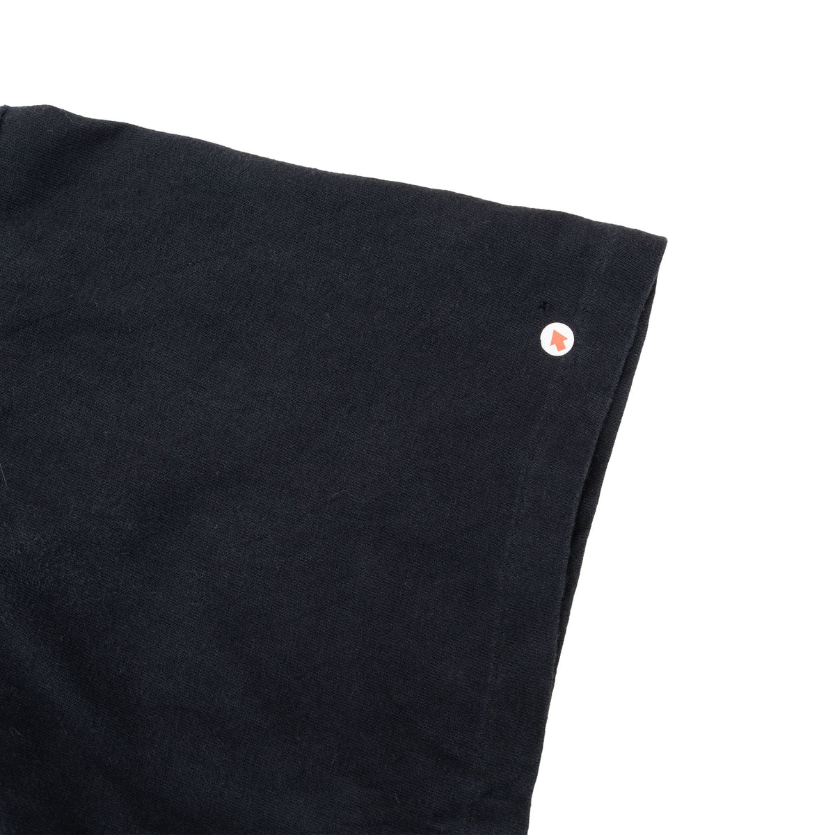 Close-up of black sleeve with a small spot indicated by an arrow marker