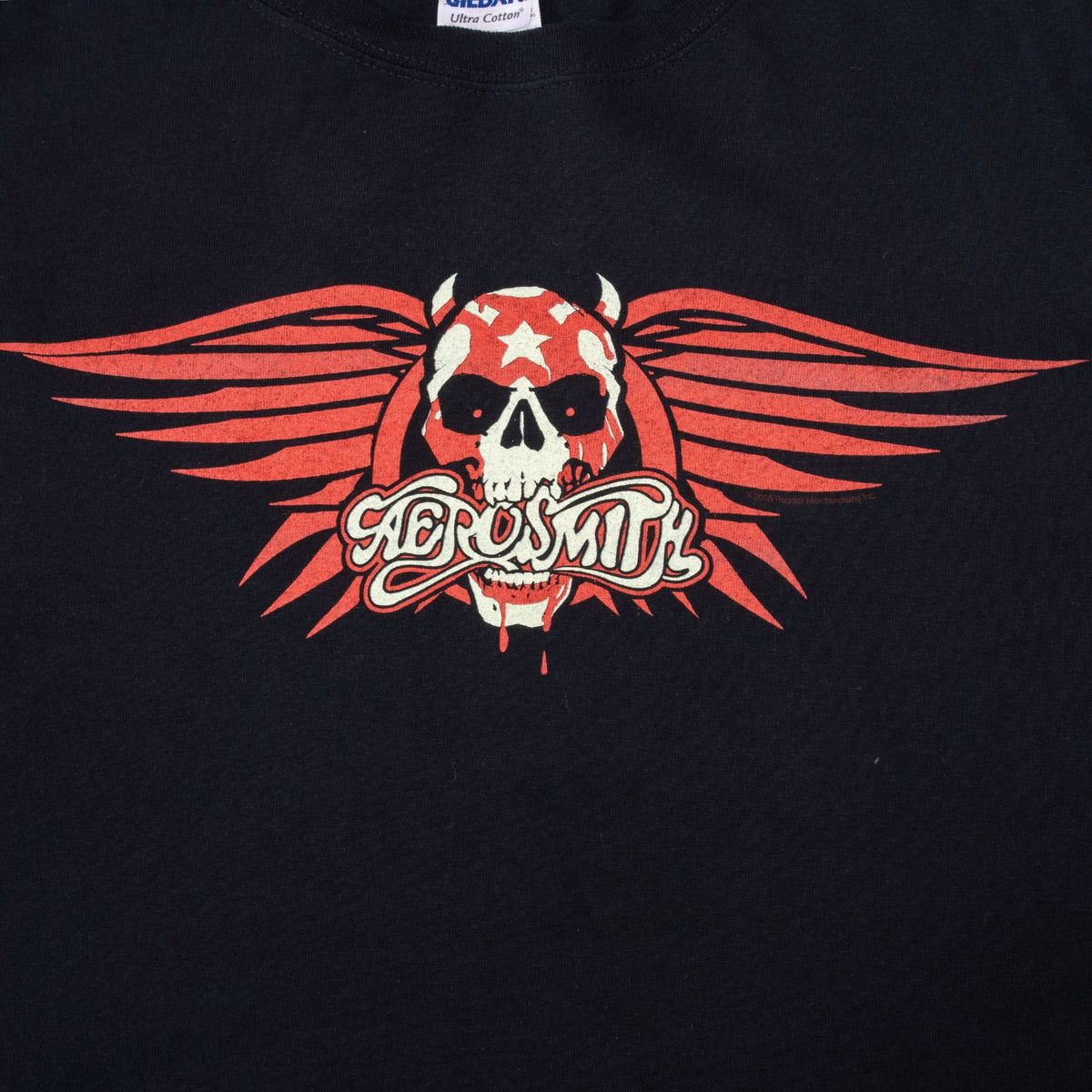 Close-up of red and white Aerosmith logo, horned skull, and wings front graphic