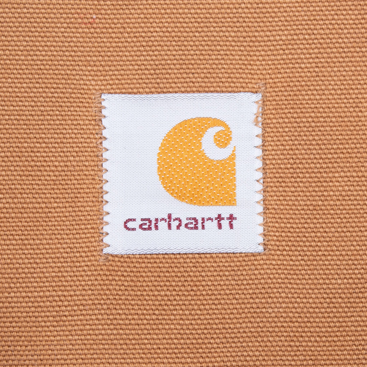 Close-up of square Carhartt logo patch stitched inside brown hunter vest