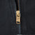 Close-up of brass-tone front zipper on black Carhartt jacket
