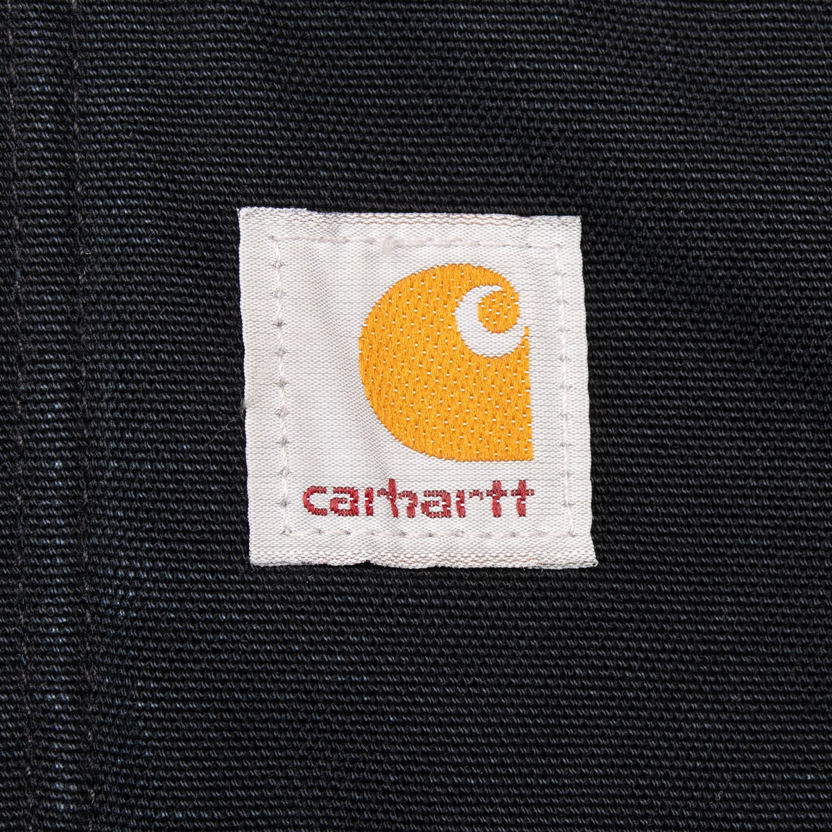 Close-up of Carhartt logo patch stitched on black fabric