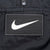 Close-up of centered white Nike Swoosh patch on black windbreaker