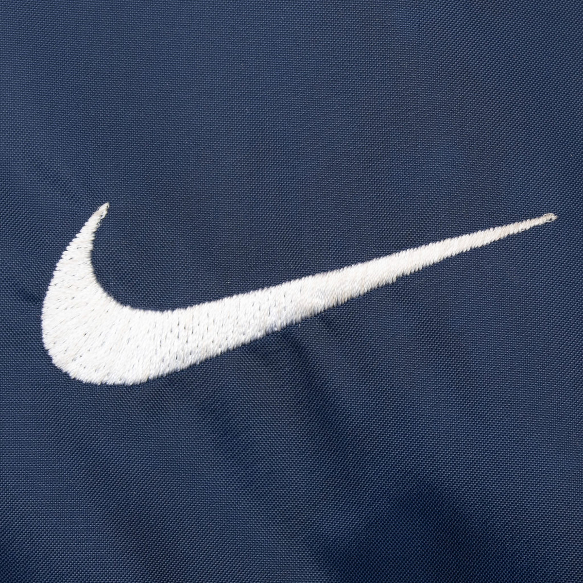 Close-up of white embroidered Nike Swoosh on navy fabric