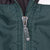 Close-up of Nike-branded metal zipper pull on green windbreaker
