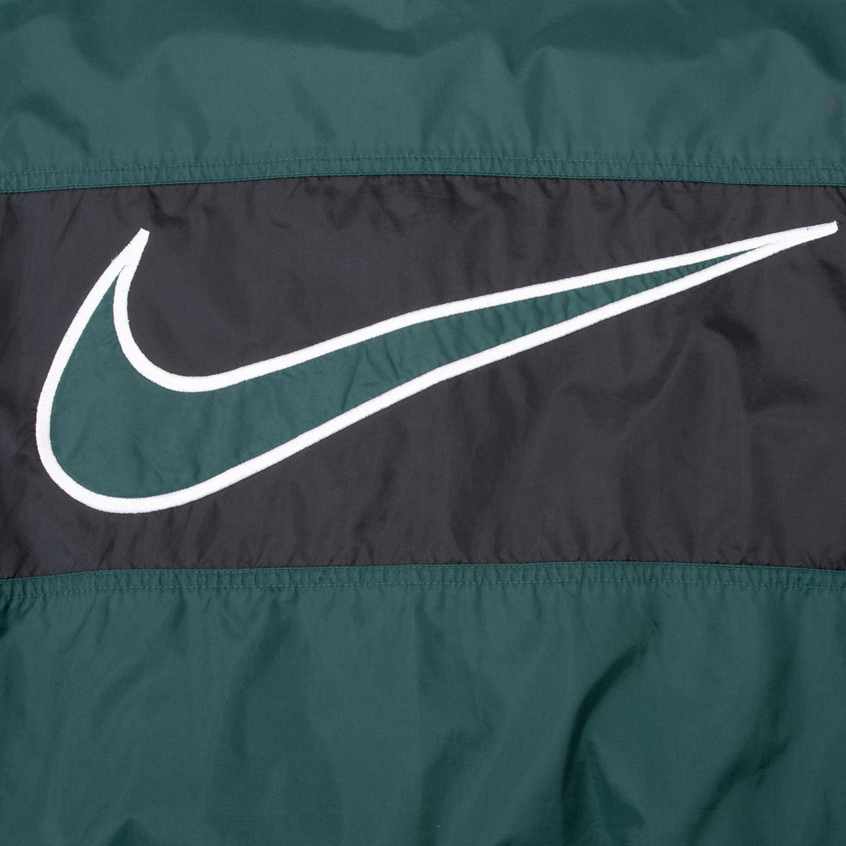 Close-up of oversized green and white outlined Nike Swoosh on black back panel