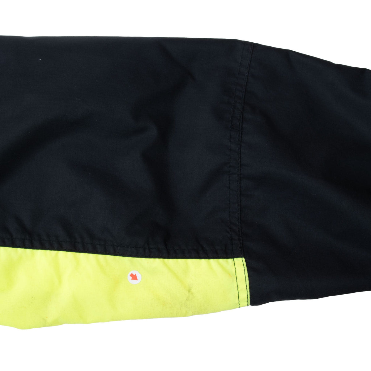Black jacket sleeve with neon green panel and a small reddish mark