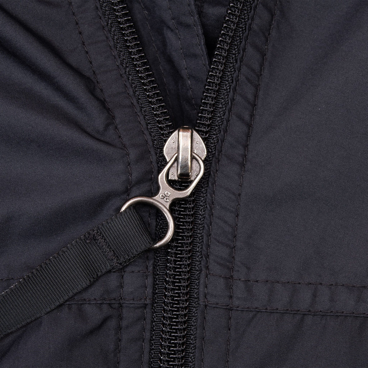 Close-up of branded metal zipper pull on black Nike ACG windbreaker