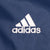 Close-up of white embroidered Adidas chest logo on navy fabric