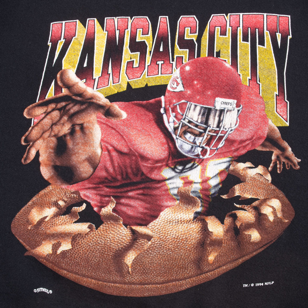 Close-up of front Kansas City Chiefs player bursting through a football print