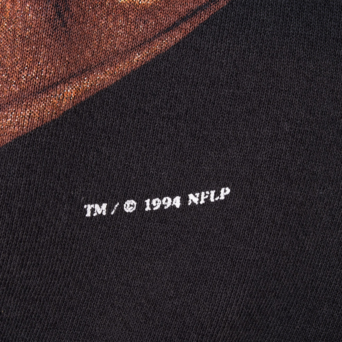 Close-up of 1994 NFLP copyright mark printed on black sweatshirt fabric