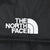 Close-up of white The North Face logo embroidery on black jacket shell