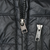 Close-up of main and chest pocket zipper pulls on black Patagonia parka