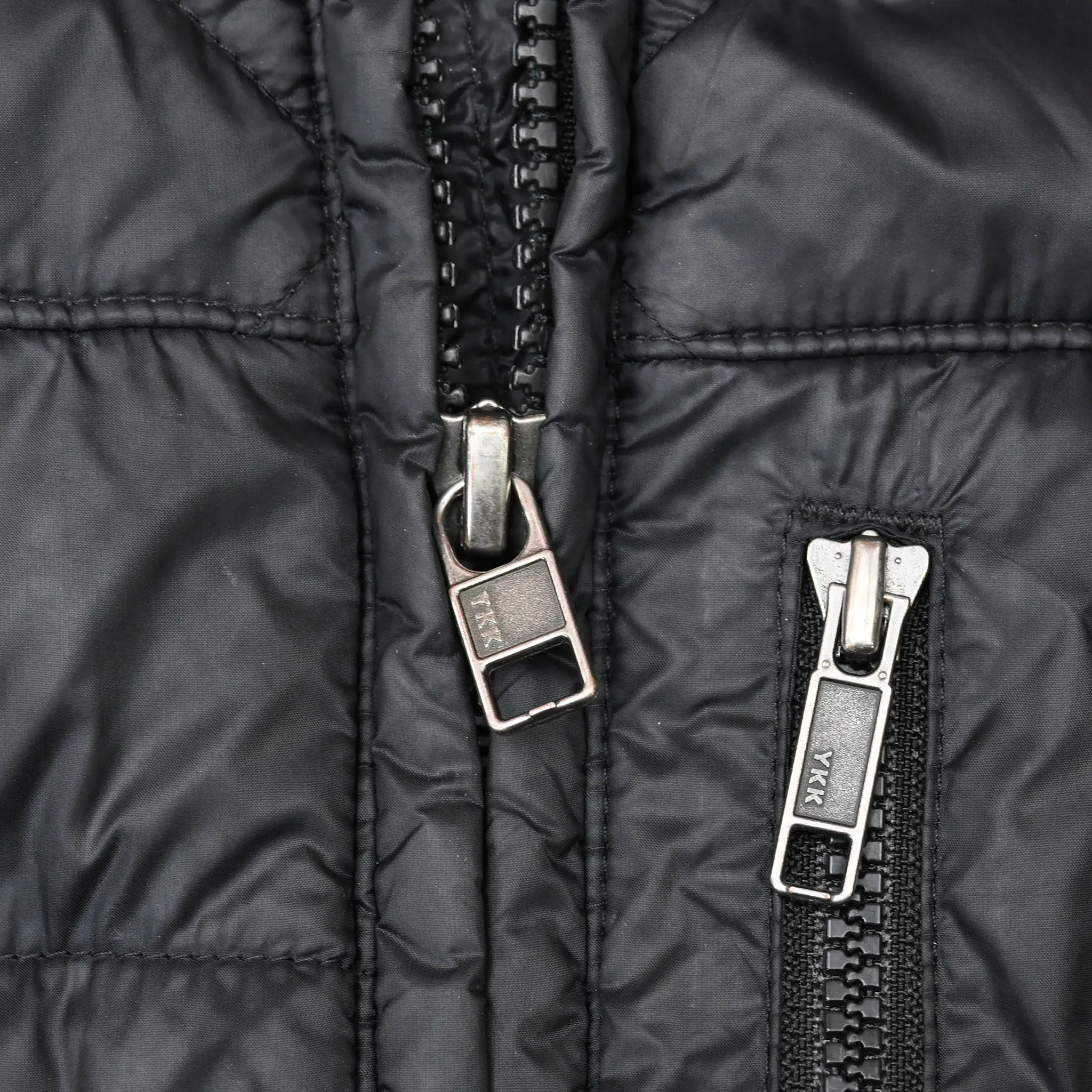 Close-up of main and chest pocket zipper pulls on black Patagonia parka
