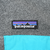 Patagonia logo above turquoise chest pocket on dark grey fleece
