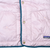 Pale pink puffer front detail with snap closure, two pockets, teal trim, and Patagonia patch