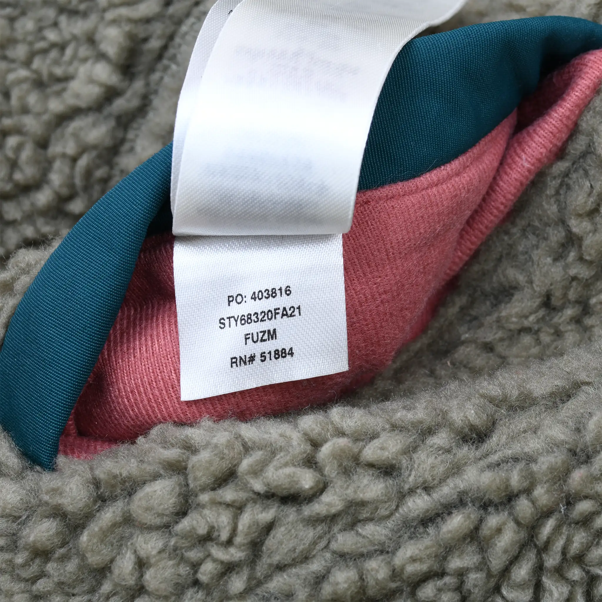 Interior style tag marked STY68320FA21 among olive fleece, teal trim, and pink lining