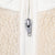 Close-up of metal zipper pull and white trim on beige fleece jacket