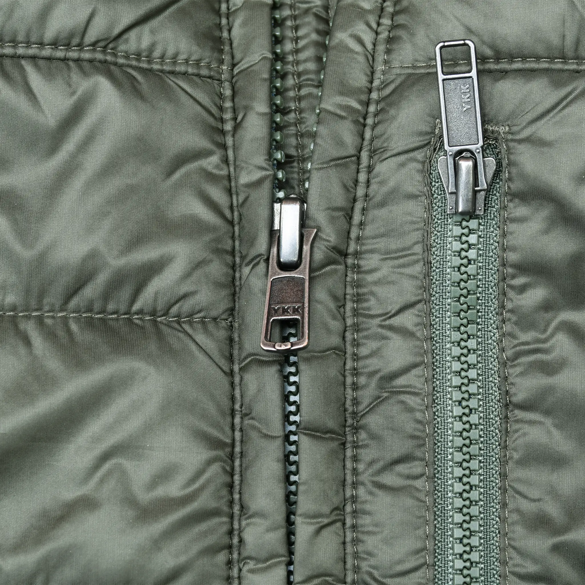 Close-up of front and chest pocket zippers on green Patagonia jacket