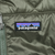 Close-up of Patagonia logo patch on green quilted chest