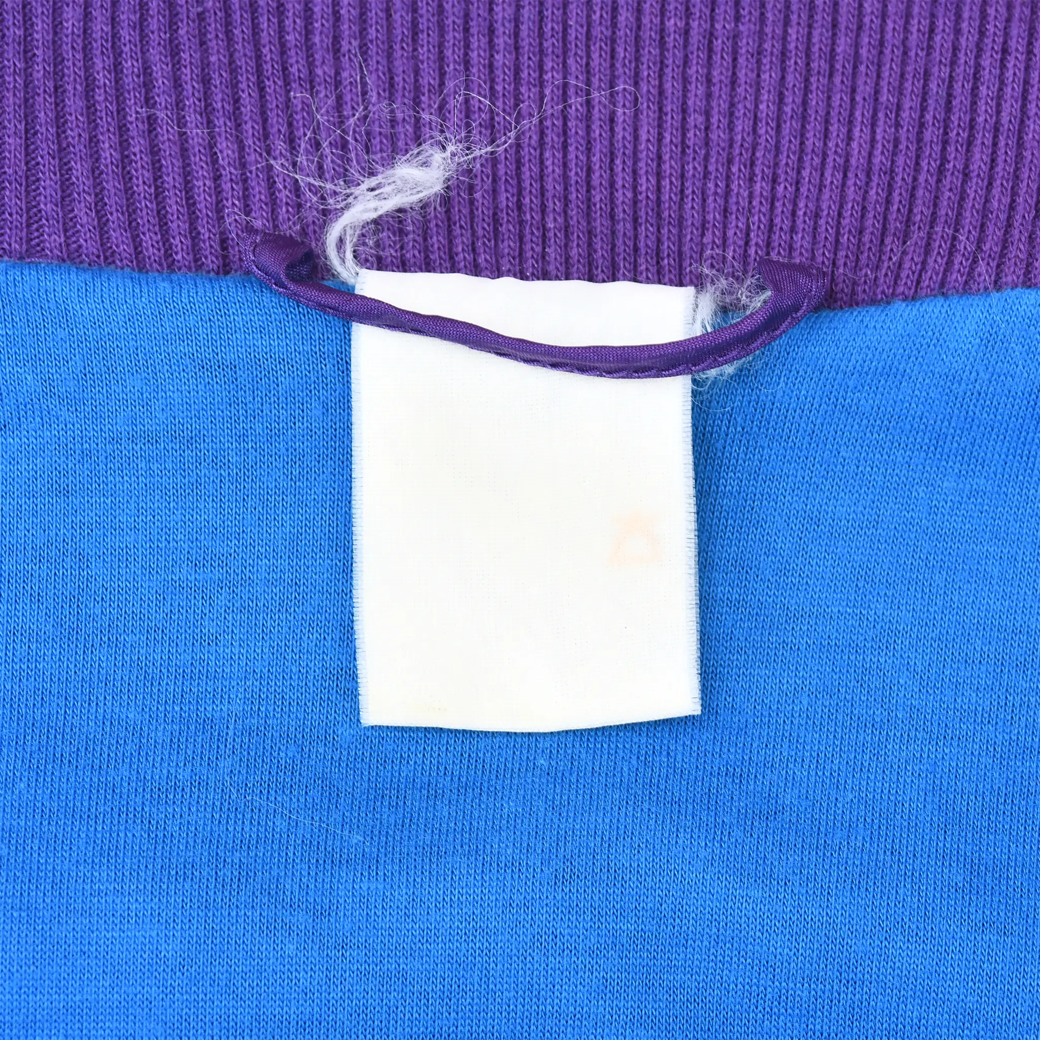 Close-up of faded interior neck tag beneath purple ribbed collar