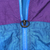 Close-up of blue front zipper with black ring pull and purple-blue color blocking