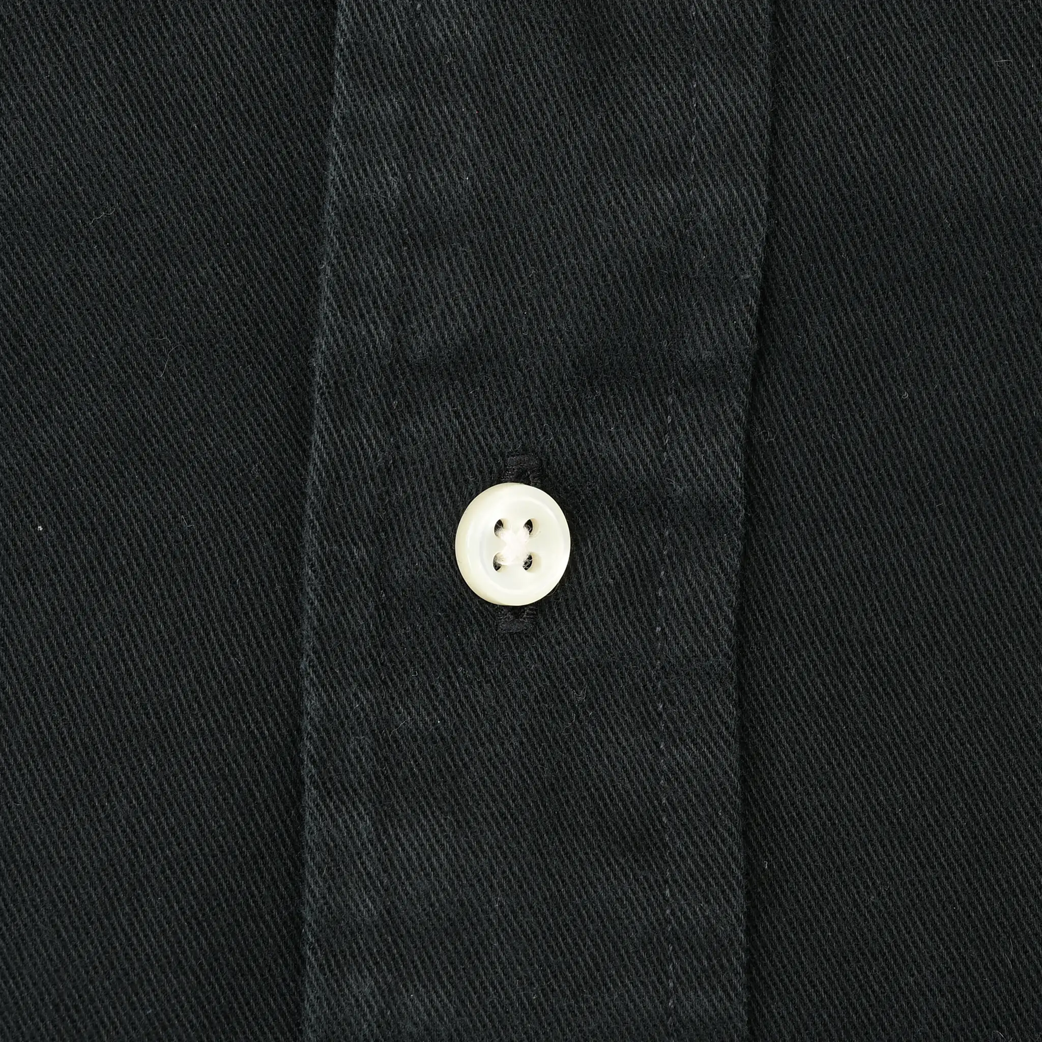 Close-up of white button and stitching on black shirt fabric