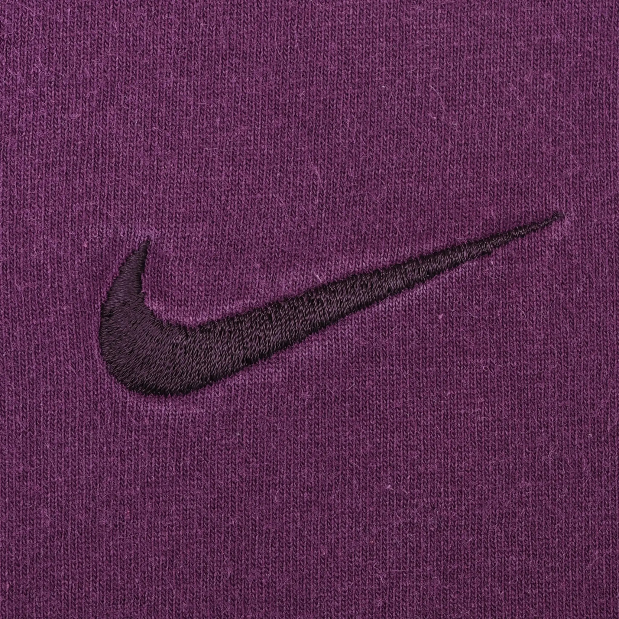 Close-up of dark Nike Swoosh embroidery on purple fabric