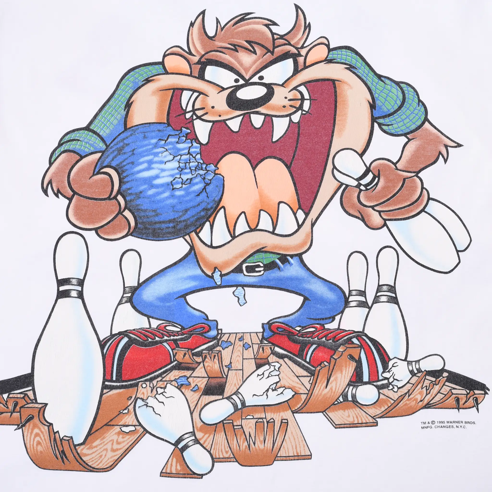 Close-up of Taz holding a blue bowling ball amid pins and broken wood